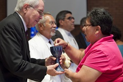 marcha-2011-15 The Rev. Noé Gonzales (left) offers Holy Communion to Nohemi Ramirez during worship in El Paso, Texas. Photo by Mike DuBose, United Methodist Communications.
