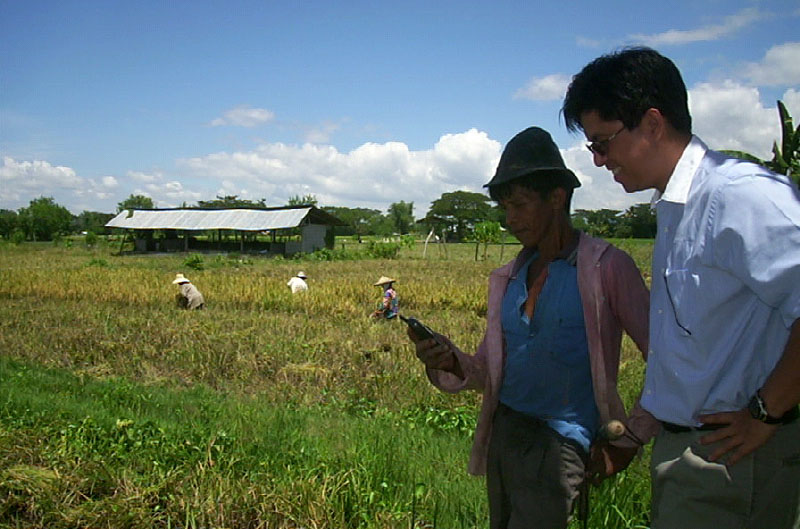 Two men in a rural area of the Philippines check a mobile phone. Photo by Ken Banks, kiwanja.net.