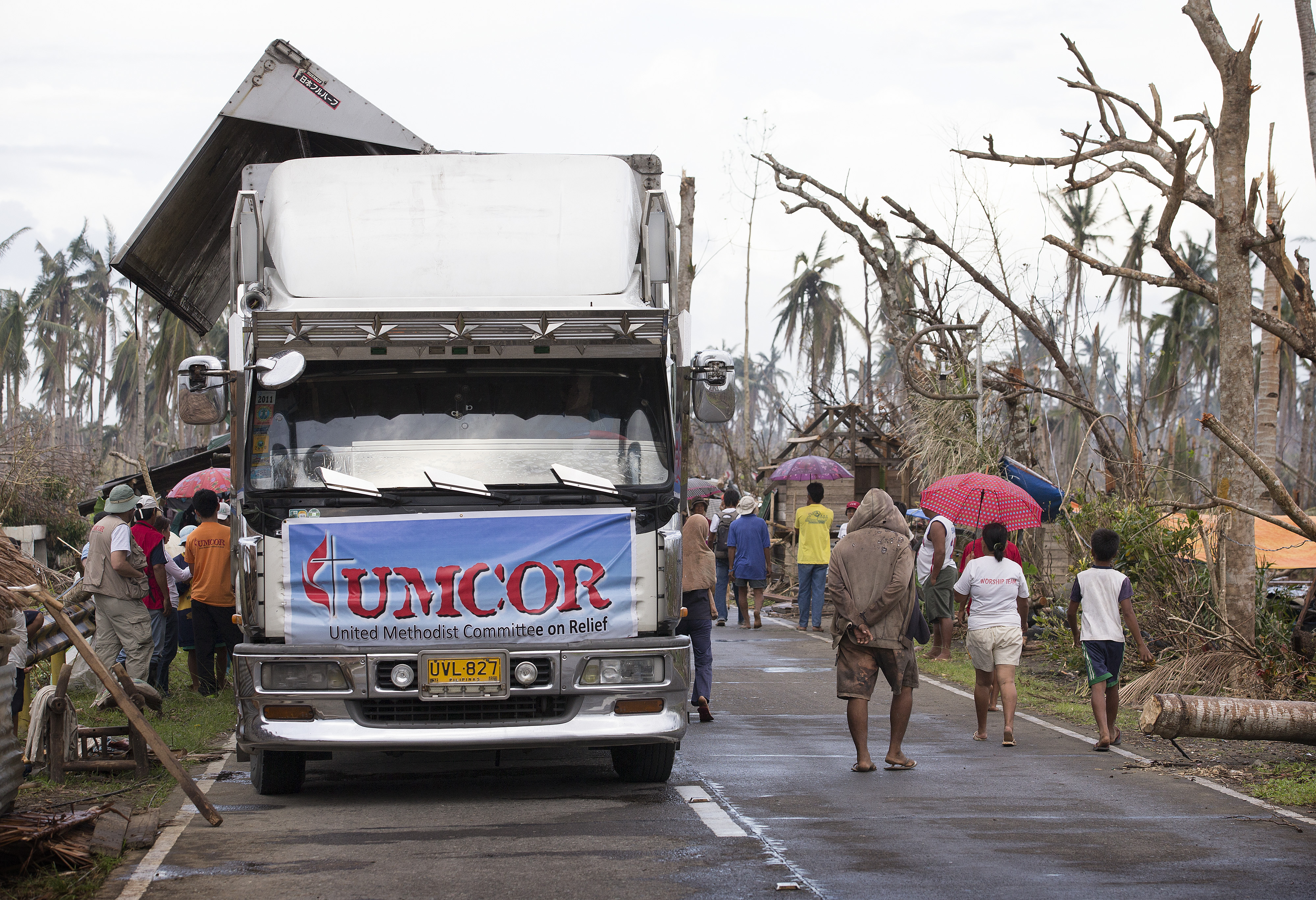 Community members walk past a food distribution site for the United Methodist Committee on Relief following Typhoon Haiyan in Dagami, Philippines. Photo by Mike DuBose, UMNS