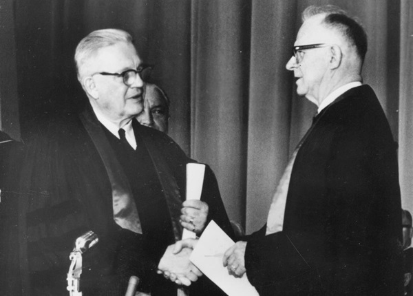 Evangelical United Brethren Church Bishop Reuben H. Mueller (left) and Methodist Bishop Lloyd C. Wicke join hands on April 23, 1968, symbolizing the merger between the two denominations. 1968 file photo courtesy of the United Methodist Commission on Archives and History; cropped from original.