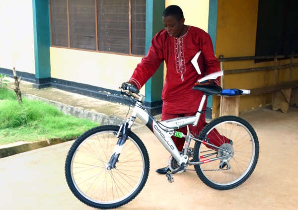 The Rev. Canon James George of the Anglican Church walks away with a new bicycle, a gift to his church after a three-day Bikes and Bibles training session in Bo, Sierra Leone. The program aims to support clergy engaged in rural evangelism by providing them with bicycles, motorcycles and Bibles to work in areas that are difficult to reach. Photo by Phileas Jusu, UMNS.