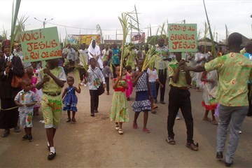 Una multitud marcha agitando palmas por las calles de Port-Bouët, Costa de Marfil, el Domingo de Ramos del 2015. Un hombre representa a Jesucristo montado en un pollino. Esta escena jubilosa es repetida por todo el país por metodistas unidos y católicos marfileños
