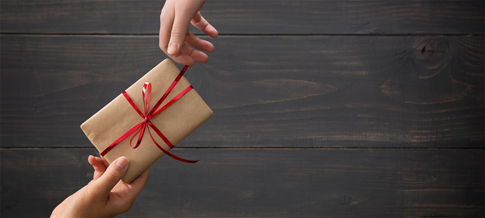 Stock photo of one hand passing a gift to another hand.