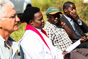 Attendees seated at dedication ceremony for the construction of a new farmhouse.