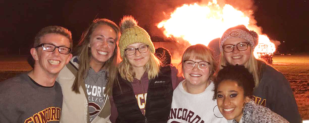 Emma Allen (center) poses with friends at a bonfire.