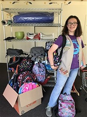 Elena poses with backpacks full of supplies.