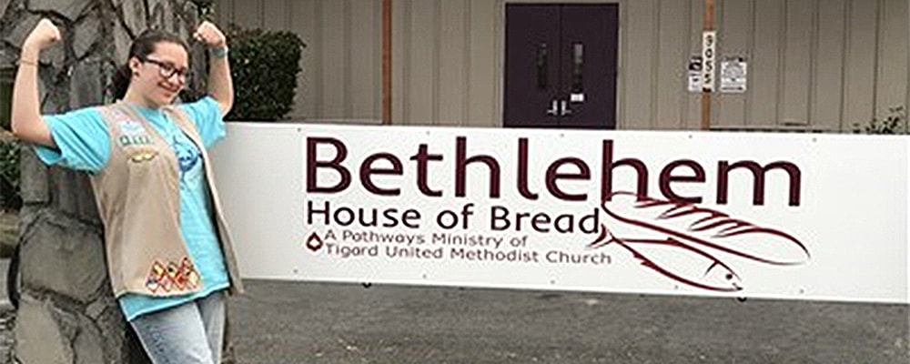 Elena Villarreal stands in front of sign at Bethlehem House of Bread. Courtesy photo.