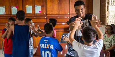 Vinicius Guimarães dos Santos, an educator with Shade and Fresh Water, plays a game with some of the students at the Liberdade site in Brazil. Teca Greathouse is far right in the background. Photo: Mark Greathouse.