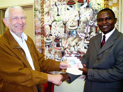 Rev. Meinhardt hands donation to Daniel N’zengya. Courtesy photo.