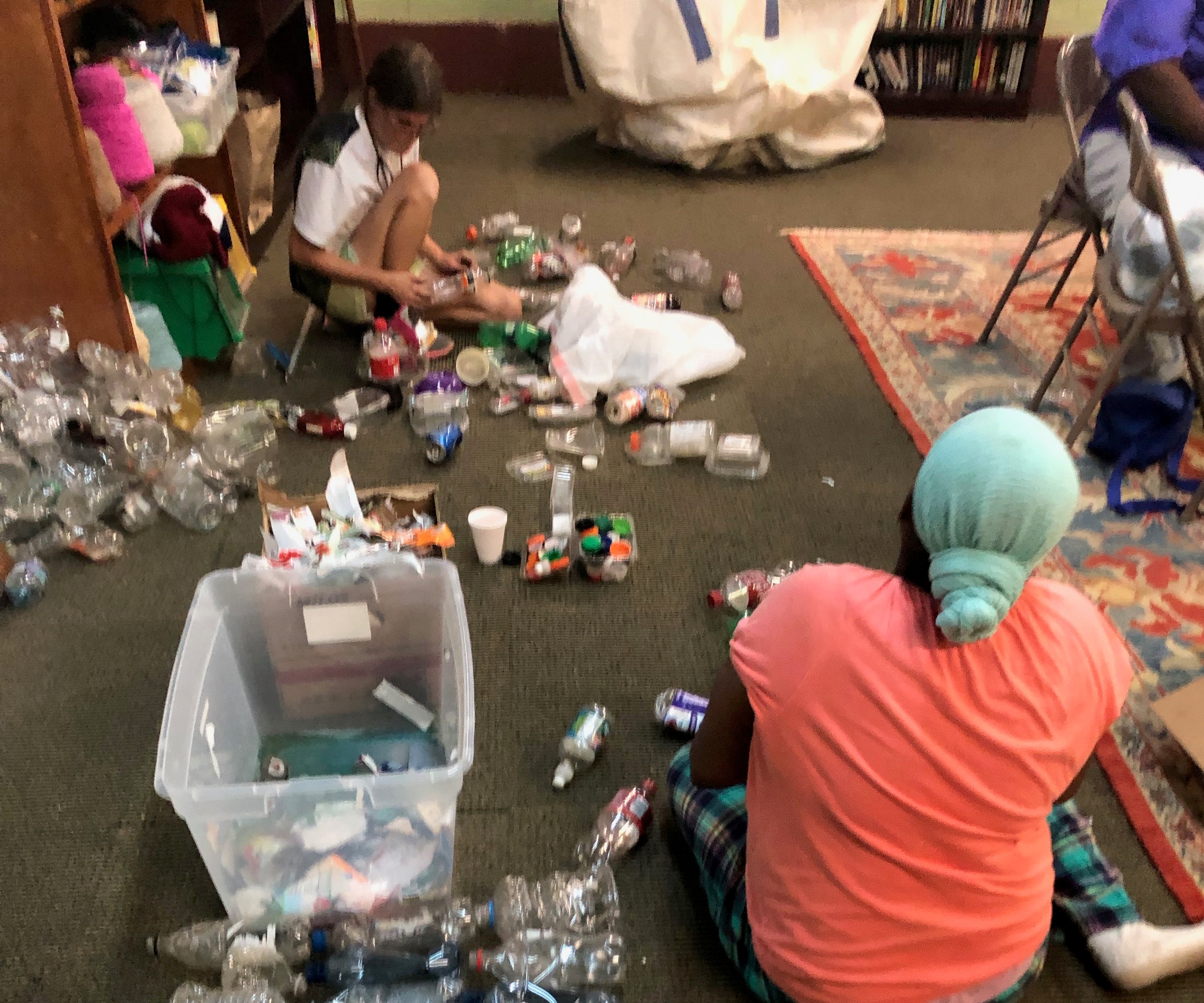 Left to Right: Amber Harrison and Celeste Vanhoose (back to camera) de-labeling and crushing plastic bottles for shredding. Photo: Mollie Erickson