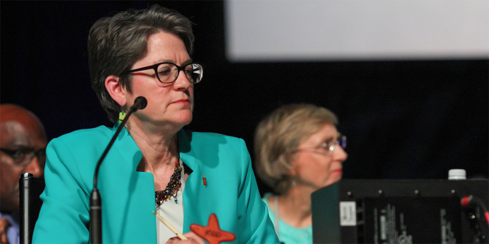 Bishop Sally Dyck presides over a discussion of the church budget during the 2016 United Methodist General Conference in Portland, Ore. With the next General Conference delayed until 2021, the board of the denomination’s finance agency decided it had no choice but to continue with the apportionment formula approved in 2016. 