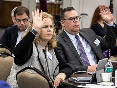 Christine Dodson and the Rev. David Bell, General Council of Finance and Administration board members, raise their hands during a meeting at Scarritt Bennett Center in Nashville, Tenn. The board voted to send the smallest budget the General Conference in more than 30 years. Photo by Kathleen Barry, UM News.