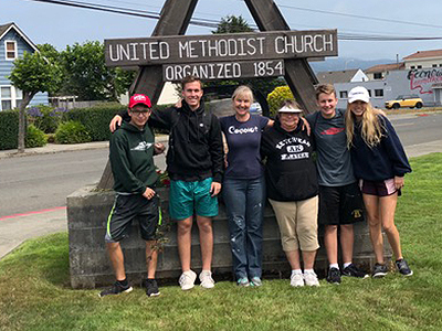 Trent Hisey, second from left,  poses with youth group in front of congregation sign.