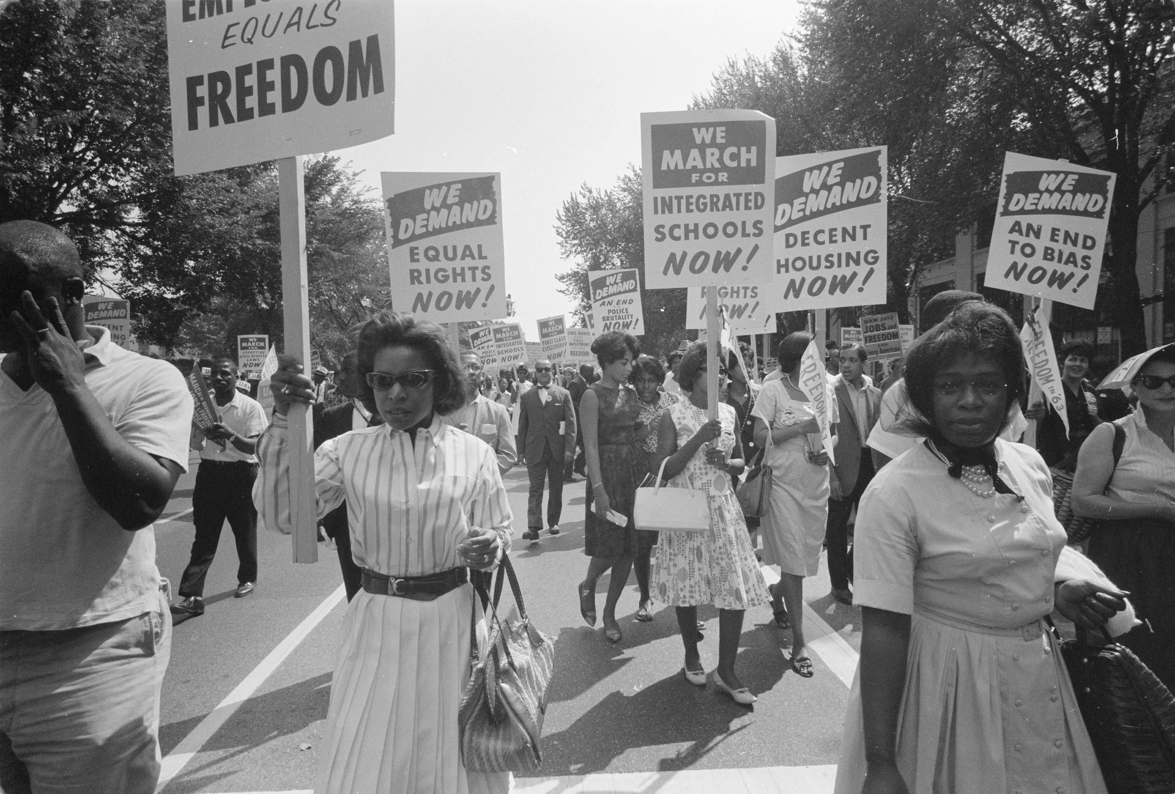 Procession of African Americans carry signs for equal rights, integrated schools, decent housing, and an end to bias at the March on Washington for Jobs and Freedom on August 28, 1963. Photo by Warren K. Leffler, property of Library of Congress  