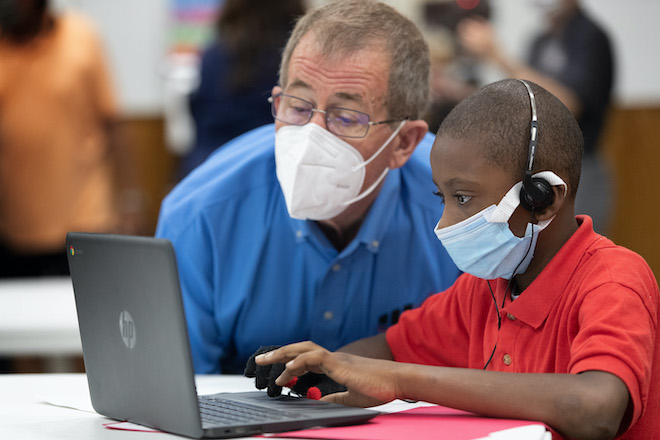 Bishop Scott Jones visits with 3rd grader Dondren Wilson on the first day of the Sanctuaries of Learning program at Trinity United Methodist Church in Houston. The program, started by the Texas Conference of The United Methodist Church, offers a safe space, internet access and other resources in area churches, allowing parents to return to work and their children to continue their education during the COVID-19 pandemic. Photo by Mike DuBose, UM News.