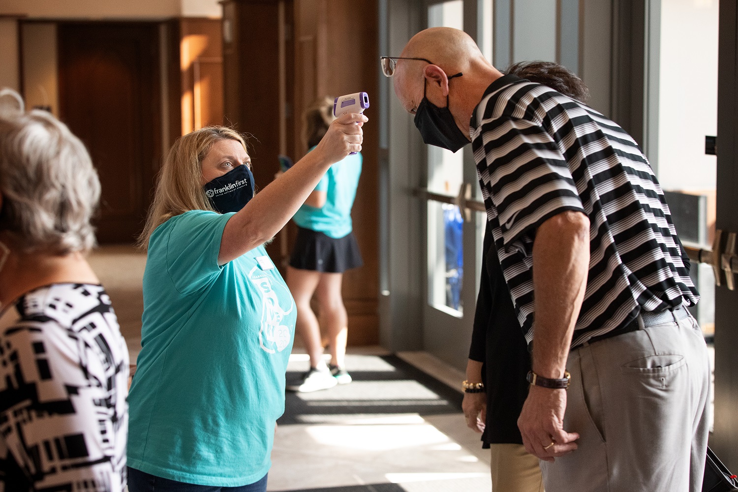 Volunteer Jennifer Jannetty checks James Crigger’s temperature as he arrives for worship at Franklin (Tenn.) First United Methodist Church. The church, which recently returned to in-person worship, has adopted safety protocols to help prevent the possible spread of COVID-19. Photo by Mike DuBose, UM News.