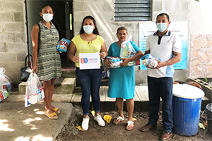A member of a Lutheran Synod youth group helping to distribute relief supplies (holding the UMCOR sign) poses with a family that has just received their food rations. PHOTO: COURTESY OF THE SALVADORAN LUTHERAN SYNOD