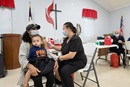 Camisha Henson holds her son Welles in her lap while receiving a COVID-19 vaccination from Tabitha England, RN, during a clinic at St. Mark’s United Methodist Church in Charlotte, N.C.