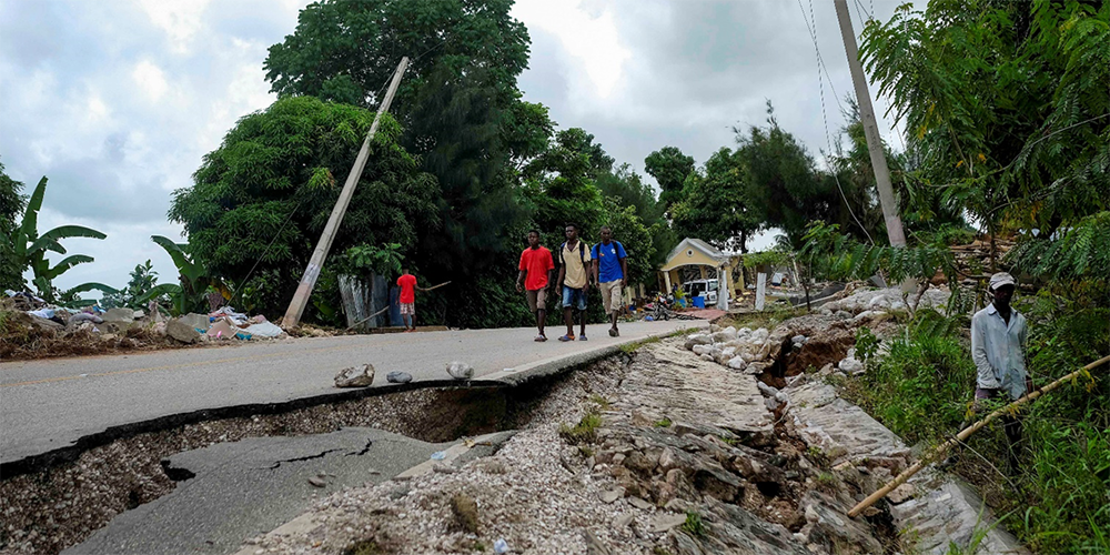 Residents walk on a damaged road in Rampe, Haiti, Wednesday, Aug. 18, 2021, four days after 7.2-magnitude earthquake hit the southwestern part of the country. (AP Photo/Matias Delacroix)