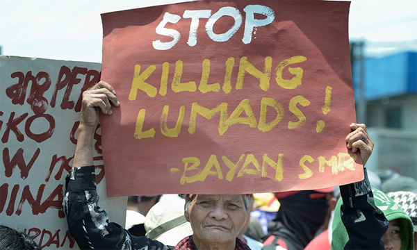 An Indigenous man holds a sign during a demonstration in 2016 outside a military base in Davao, on the southern Philippine island of Mindanao. Hundreds of Indigenous (known locally as Lumads) were living in a church compound in the city, chased out of their rural villages by paramilitary squads. Photo © Paul Jeffrey, Life on Earth Pictures An Indigenous man holds a sign during a demonstration in 2016 outside a military base in Davao, on the southern Philippine island of Mindanao. Hundreds of Indigenous (known locally as Lumads) were living in a church compound in the city, chased out of their rural villages by paramilitary squads. Photo © Paul Jeffrey, Life on Earth Pictures
