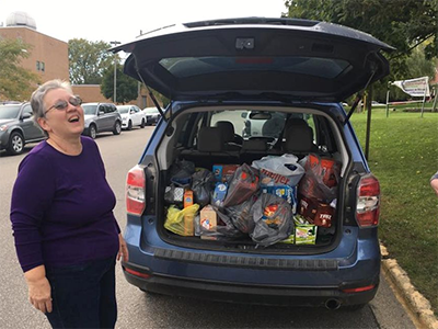 In October 2018, Deb Johnson, Chair of the Wesley Foundation Board at Ferris State University, rejoices over the carload of groceries from South Community UMC. Since 2016, the Big Rapids Wesley House has supported a Student Food Pantry at FSU. ~ Facebook/Big Rapids Wesley House