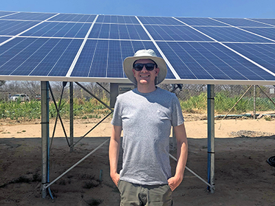 Dr. Gareth poses in front of solar panels. Courtesy photo.