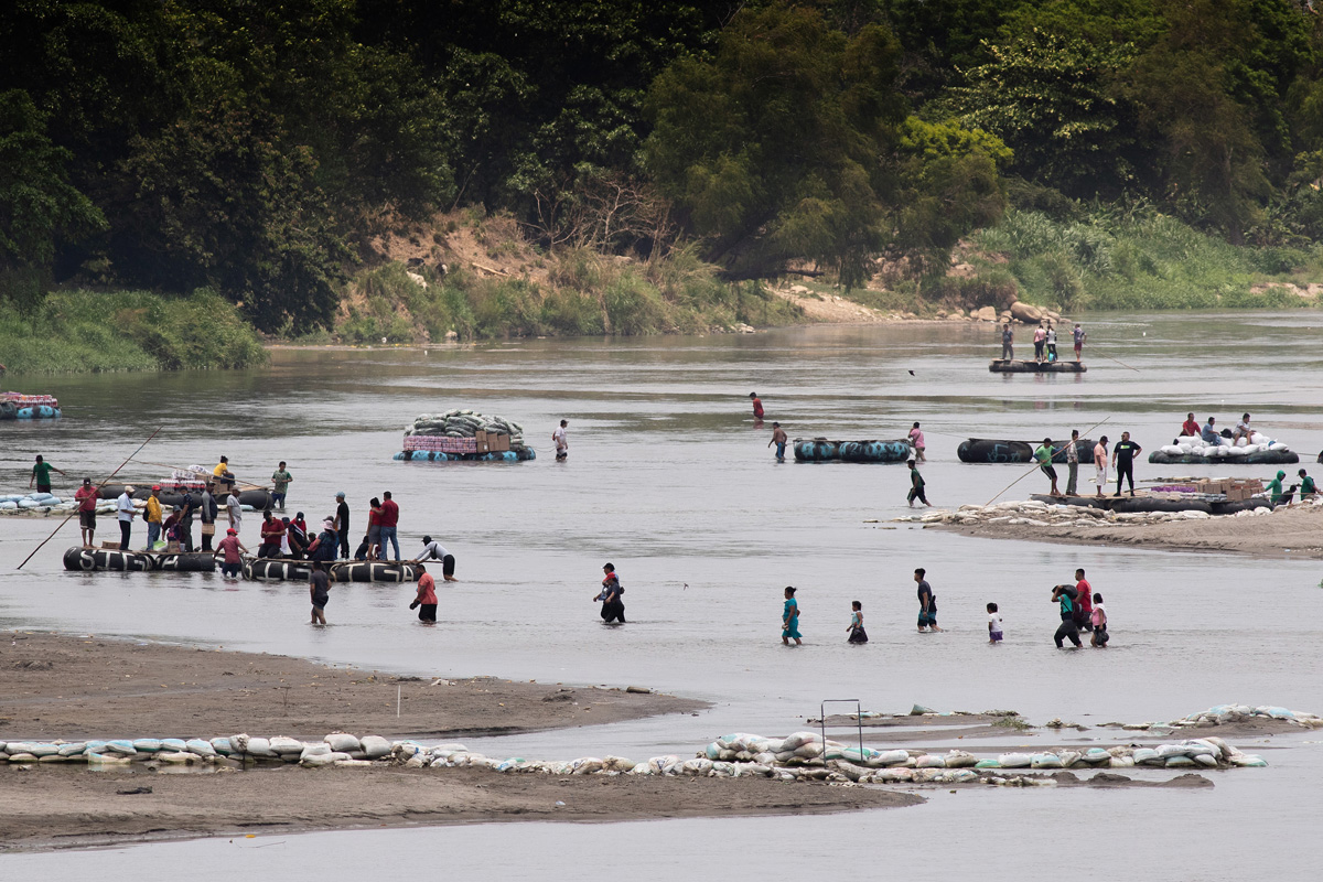 People wade or ride rafts made from inner tubes across the Suchiate River, which forms part of the border between Guatemala and Mexico, near Ciudad Hidalgo, Mexico. The busy, informal crossing is used by migrants as well as by people hauling commercial cargo in both directions. A ride across on one of the inner tube rafts usually costs between 10 and 20 Guatemalan quetzals, roughly $1.25-$2.50 U.S. Photo by Mike DuBose, UM News.
