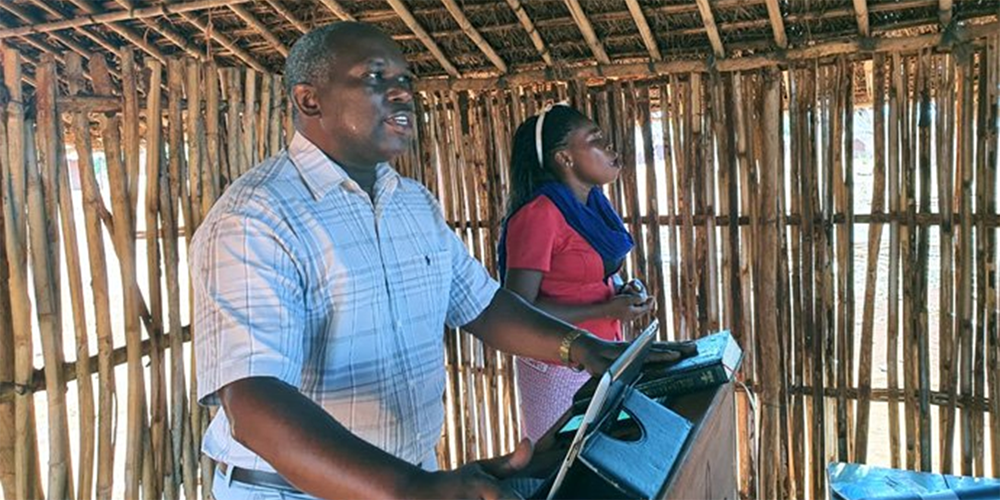 Arlindo Jossias Sambo preaches in Ninga, Mozambique, at a new United Methodist church that he started in 2021, while Celine Miguel translates. Sambo graduated from Africa University in 2008 with a degree in economics and has worked with the National Roads Administration — Public Institute (ANE-IP) since graduating. An enthusiastic volunteer for the church, he helped to establish two United Methodist congregations. File photo by Michaque Ali.