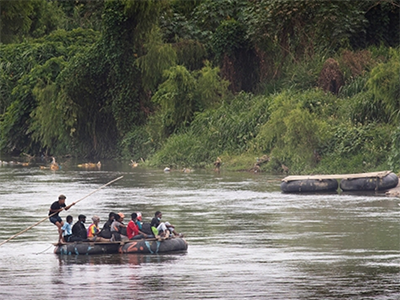 A guide using a raft made from inner tubes ferries people across the Suchiate River from Guatemala into Mexico near Ciudad Hidalgo. Migrants, many of them fleeing violence, routinely cross the border into Mexico here, many of them hoping to eventually make their way to the United States. PHOTO: MIKE DUBOSE, UM NEWS