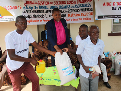 The Bishop Daniel Lunge assisted by UMCOR volunteers including Armand Osango and Placide gave the bag of rice to Papa Jean Okito, one of the victims. The Church brought food to displaced people who fled clashes between two communities following a forest conflict. Photo by Francois Omanyondo, UM News.