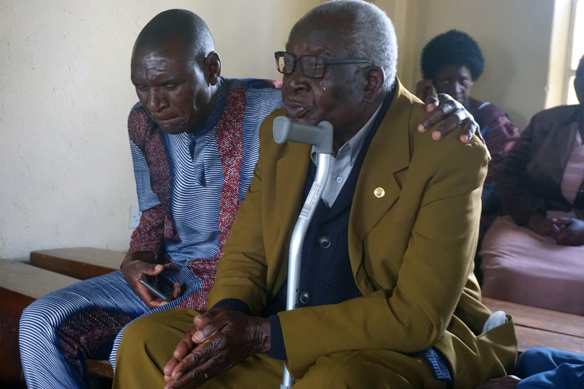 Toendepi Samson Marikasi sobs with grief over the loss of his wife, Alice Marikasi, 87, and her sister, Ellah Muti, 90, during a special memorial service at St. James Hwedza United Methodist Church in Zimbabwe. Pastor Daniel Luckson consoles him. United Methodist churches in Zimbabwe held services where people who lost loved ones during COVID-19 could gather to console one another and celebrate life — things they were unable to do during pandemic restrictions. Photo by Kudzai Chingwe, UM News.