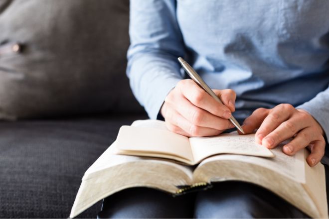 Person studying Bible with notebook 660x440. Image by Canva.