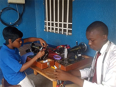 Two teenagers from the Coeur d'une Mère orphanage sew clothes at the United Methodist New Life Skills Training Center in Mpasa, Congo. Missionary Innocent Afful works with 15 orphanages and four vocational training centers offering soap-making and sewing among other trades. Photo courtesy of Innocent Afful.