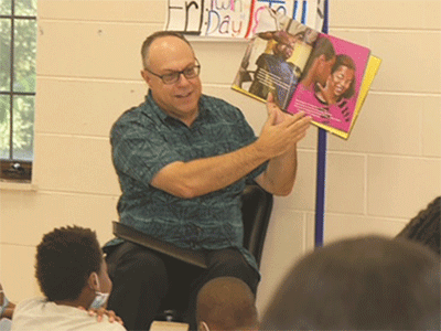 Children listens to a volunteer read a story at the St Mark's Children's Defense Fund Freedom School's summer program. Courtesy photo.
