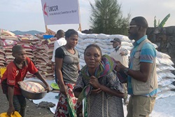 John Lusulu, financial assistant with the United Methodist Committee on Relief’s disaster management office in eastern Congo, helps a young woman carry food during a distribution operation for people displaced by war in Goma, Congo. Each household received one month’s food aid and essential non-food items. Photo by Chadrack Tambwe Londe, UM News.