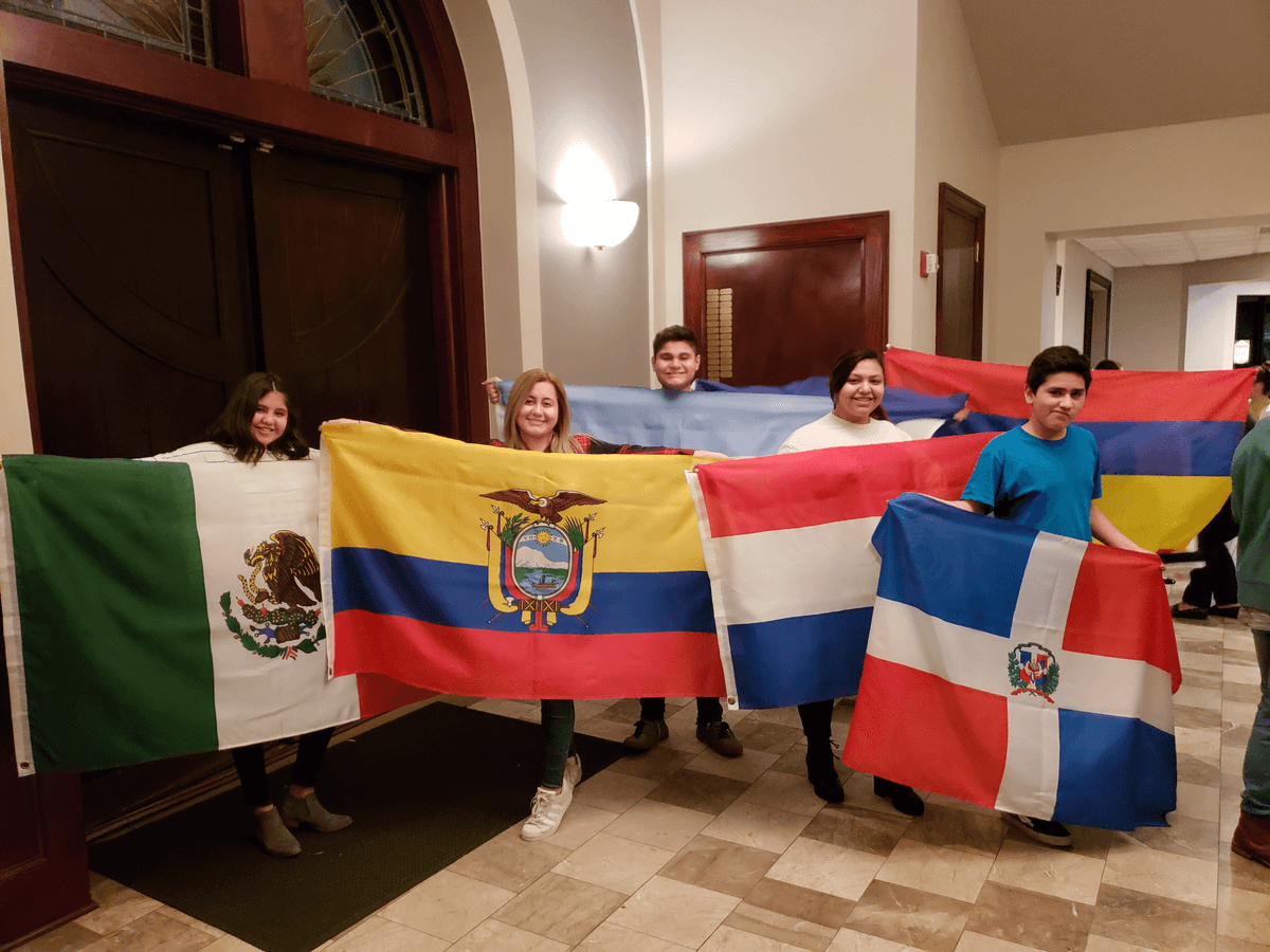 Children proudly hold flags that represent their national heritage during a worship service.
