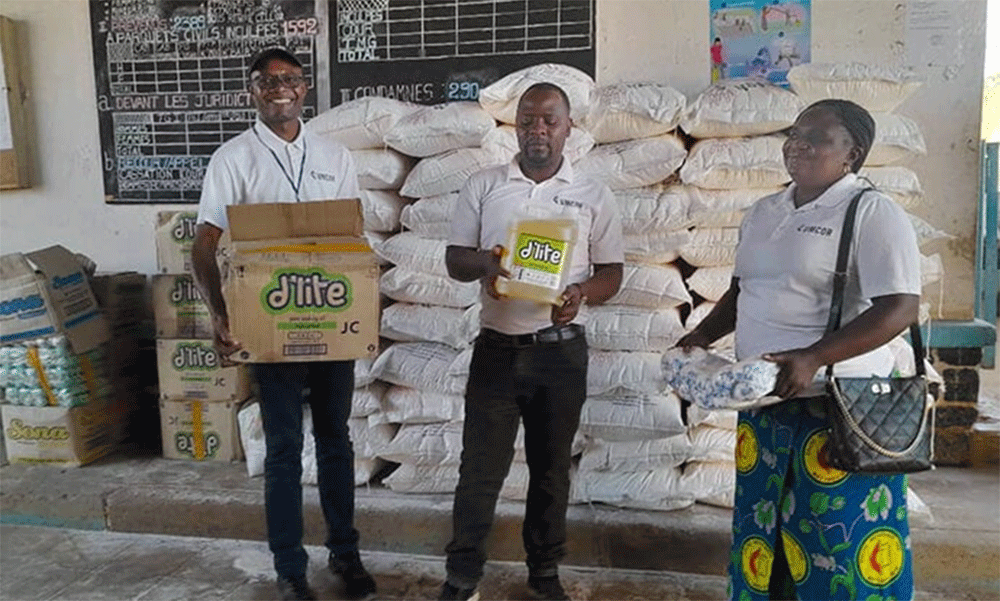 The Rev. Caleb Mbaz (left), coordinator of the Disaster Management Office for the South Congo Episcopal Area, carries a box containing vegetable oil for inmates at Kasapa Central Prison near Lubumbashi, Congo. Joining him are Disaster Management team members Kasongo Kilundu Olivier and Louise Tshiwengo. The United Methodist Church in Southern Congo distributed more than 16 tons of food and other supplies to the prison with support from the United Methodist Committee on Relief. Photo by Christian Kasweka, UM News.