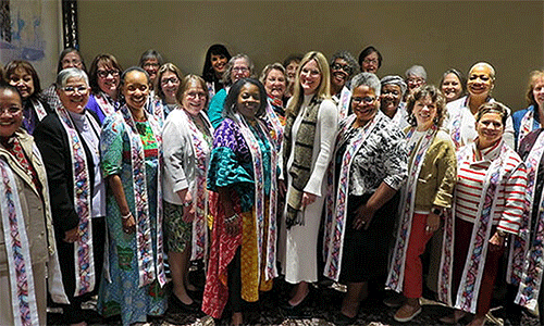 The Rev. Stephanie York Arnold (center), the new top executive of the United Methodist Commission on the Status and Role of Women, stands with 26 active and retired women bishops. York Arnold presented the bishops with stoles made by her mother. “I hope you will wear these when you serve communion, when you open the table wide for all to come and feast on the grace of our Savior,” York Arnold told the bishops. Photo by Heather Hahn, UM News.