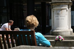 Contemplative pilgrims sit beside the tomb of John Wesley, located in a courtyard behind Wesley's Chapel in London. Photo by Kathleen Barry, United Methodist Communications