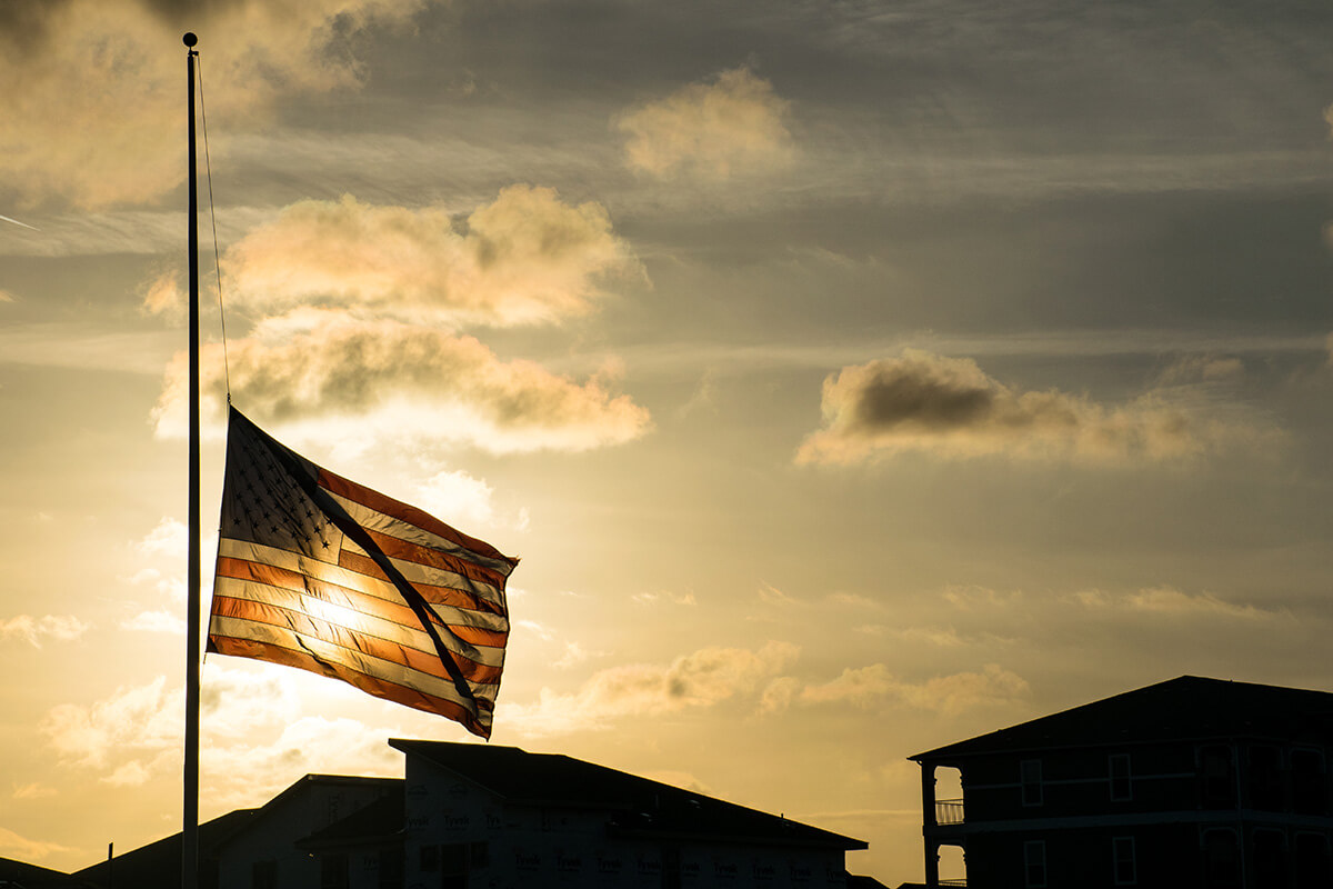 An American flag waves at half-staff in 2018 after the shooting at Marjory Stoneman Douglas High School in Parkland, Florida. Flags are standing at half-staff again after the Sept. 10 assassination of an activist on a university campus. United Methodist bishops are urging members to act as peacemakers to help put an end to the violence. Photo by Bryan Roschetzky, iStock.