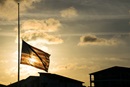 An American flag waves at half-staff in 2018 after the shooting at Marjory Stoneman Douglas High School in Parkland, Florida. Flags are standing at half-staff again after the Sept. 10 assassination of an activist on a university campus. United Methodist bishops are urging members to act as peacemakers to help put an end to the violence. Photo by Bryan Roschetzky, iStock.