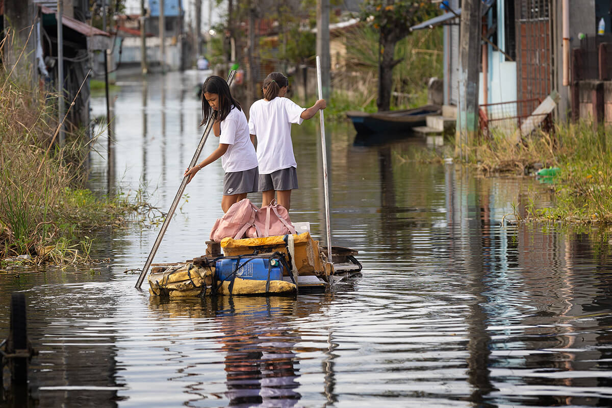 Des écolières rentrent chez elles sur un radeau artisanal qu'elles guident dans une rue inondée à Calumpit, aux Philippines, après le passage du typhon Carina en juillet 2024. Alors que le changement climatique continue d'avoir un impact sur les moyens de subsistance, les économies et les habitats à travers le monde, le Conseil des Évêques réitère son engagement en faveur de la protection de la création. Photo d'archive par Mike DuBose, UM News. 