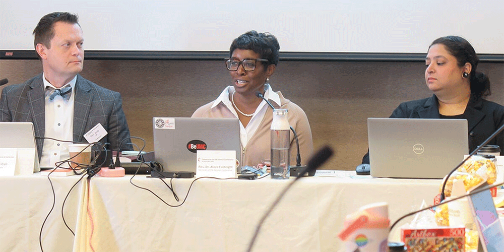 The Rev. Aleze M. Fulbright (center) celebrates the growth of The United Methodist Church in Africa as the Commission on the General Conference, meeting in Minneapolis on Nov. 11, considers setting the number of delegates for the 2028 General Conference. Sitting beside Fulbright, the General Conference secretary, are the Rev. Andy Call, the commission’s chair, and Sharah Dass, General Conference business manager. Photo by Heather Hahn, UM News.