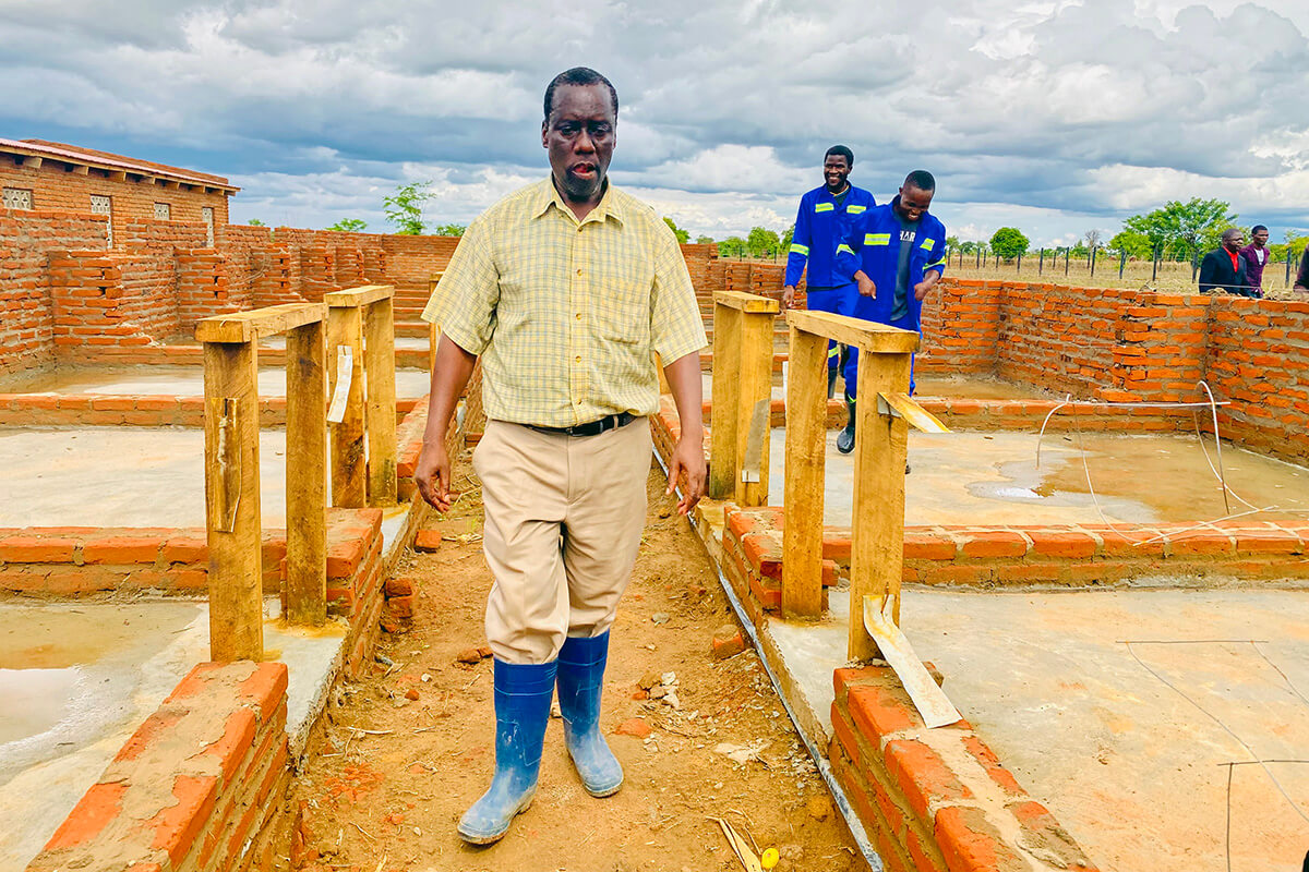 Kephus Mtambo, coordinateur du projet agricole pour la ferme laitière Mikundi à Blantyre, au Malawi, se promène dans une grange en cours de construction. La ferme est en train d'être transformée d'une installation d'irrigation précédemment négligée en un centre d'élevage moderne grâce au soutien de l'initiative agricole Yambasu, un programme du Conseil méthodiste unifié des ministères mondiaux. Photo de Francis Nkhoma, UM News.