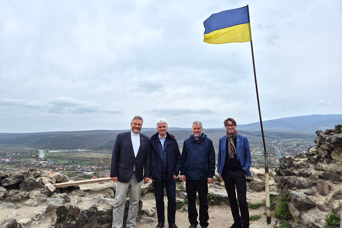 (De gauche à droite) L’Evêque Werner Philipp, le Prédicateur local István Pásztor (Hongrie), l’évêque Stefan Zürcher et l’Evêque Knut Refsdal posent sous un drapeau ukrainien au château de Nevytske, au nord d’Oujgorod, lors de leur visite en Ukraine du 26 au 30 mars. Ce voyage des évêques se voulait un signe de solidarité et un rappel à la population ukrainienne qu’elle n’a pas été oubliée. Photo gracieusement fournie par EmK-Öffentlichkeitsarbeit Allemagne, UM News.