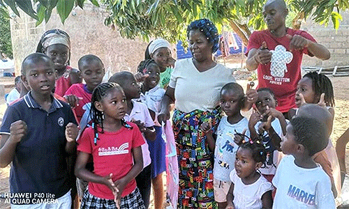 The Rev. Maria Matsinhe, a nurse and health coordinator for The United Methodist Church in Mozambique, interacts with children, including twins Paulo and Joana Buque (pictured at left), at Chucunja Elementary School in Morrumbene village. Matsinhe heads the church’s mobile clinic, which set up at the school to conduct health screenings. Photo by Antonio Wilson, UM News.