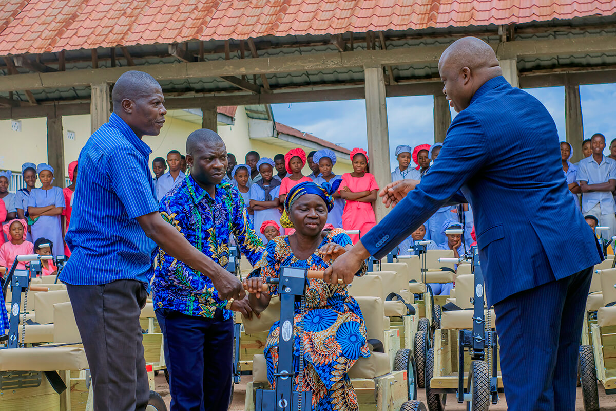 L'Evêque Mande Muyombo (à droite) aide une femme à s'installer sur son nouveau vélo adapté à Kamina, au Congo. À gauche, on aperçoit le responsable laïc Kiluba Yolola Elie et le pasteur Joseph Kasongo Mukolomone. L'Église Méthodiste Unie a distribué 97 vélos à des personnes en situation de handicap dans la Conférence du Katanga du Nord. Cette initiative est financée par des Partenaires Méthodistes de la Conférence de Géorgie du Nord. Photo de Yamba Kisonga Barthélémy, UM News.