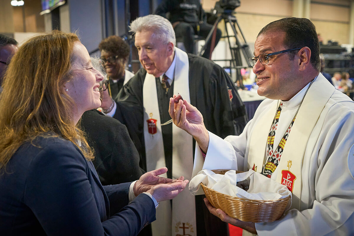 Bishop Héctor A. Burgos Núñez, who leads the Upper New York and Susquehanna conferences, distributes communion to participants during opening worship service on April 23, 2024, at General Conference in Charlotte, N.C. Next to him, also distributing communion, is Horizon Texas Conference Bishop Rubén Saenz Jr., who is now the Council of Bishops president. A United Methodist leadership body recommends that the U.S. have 34 bishops starting in 2028. File photo by Paul Jeffrey, UM News. 