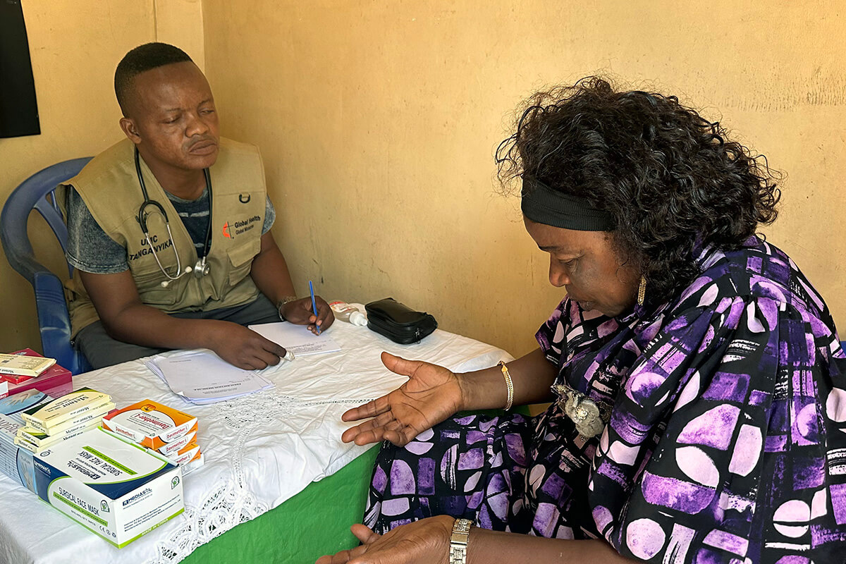 Dr Gustave Ngoy, responsable du programme de lutte contre le paludisme au sein de l’équipe de coordination médicale de la région épiscopale du Tanganyika, s’entretient avec Cathérine Shabani lors d’une consultation dans une clinique mobile à Kalemie, au Congo. Cette femme de 60 ans, mère de 11 enfants et membre de l’Église de Jérusalem (méthodiste unie), a bénéficié d’un bilan de santé gratuit dans le cadre d’une initiative médicale financée par l’évêque Nelson Kalombo Ngoy au profit des délégués de la conférence annuelle et des populations vulnérables. Photo de Chadrack Tambwe Londe, UM News.