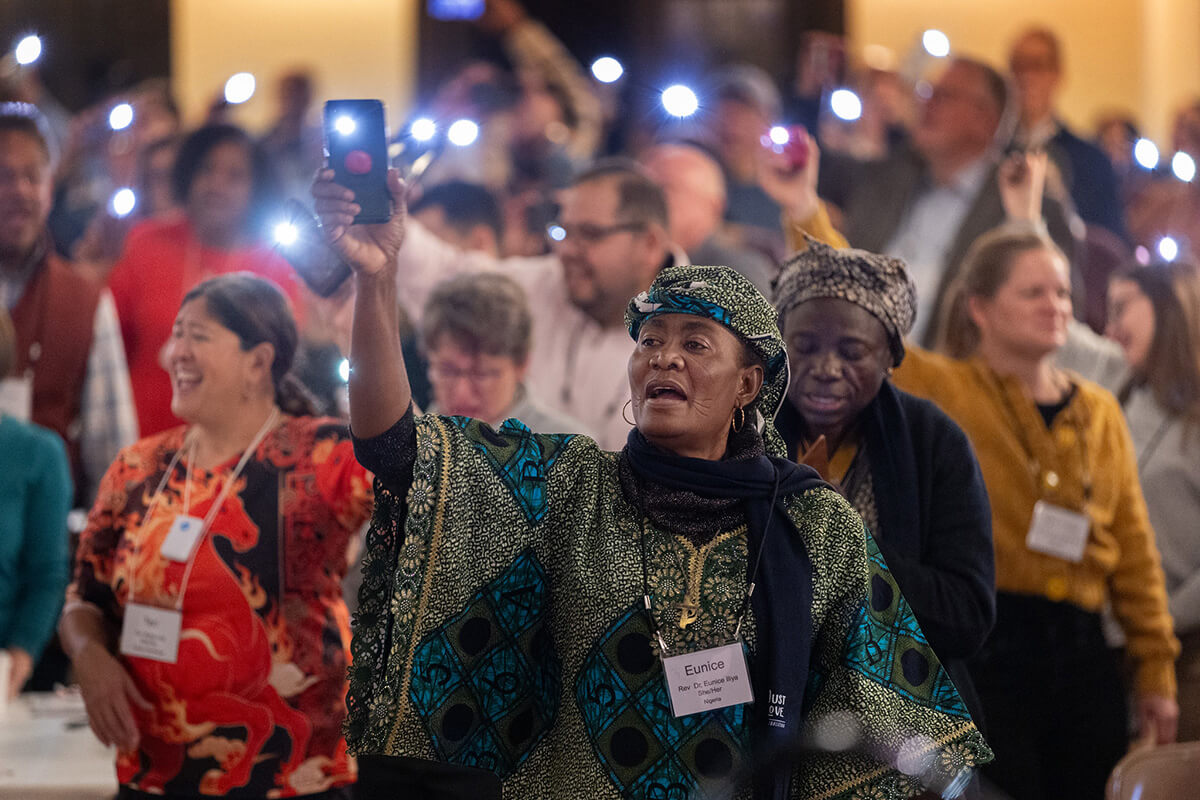 La pasteure Eunice Iliya (au centre) se joint à des centaines d’autres participants au rassemblement des responsables de l’Église Méthodiste Unie pour agiter leurs téléphones portables allumés au rythme de « This Little Light of Mine » (« Cette petite lumière qui est en moi »), à la fin du culte du matin du 23 octobre dans le sanctuaire de la Knox United Church à Calgary, au Canada, qui accueille cet événement mondial. Photo de Mike DuBose, UM News.